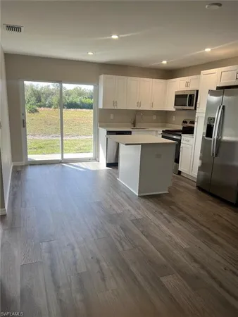 a large kitchen with stainless steel appliances granite countertop a stove a sink a refrigerator with wooden floors and cabinets