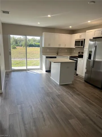 a large kitchen with stainless steel appliances granite countertop a stove a sink a refrigerator with wooden floors and cabinets