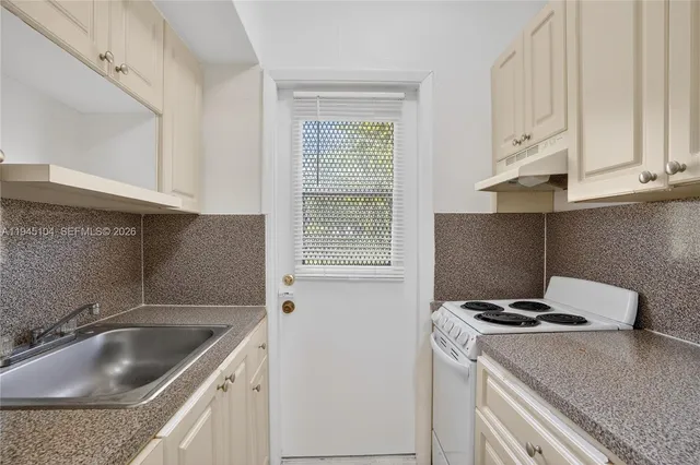 a kitchen with granite countertop a sink stove and cabinets