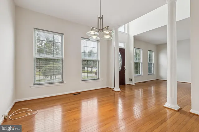 a view of an empty room with window and wooden floor