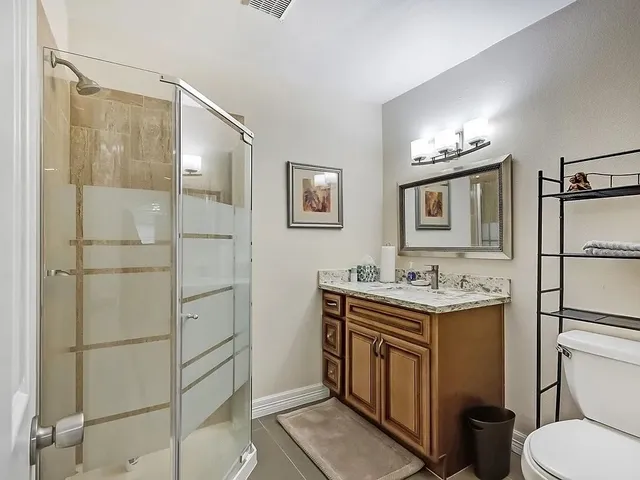 a spacious bathroom with a granite countertop sink a toilet and a mirror