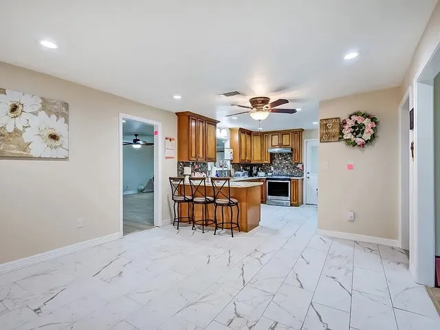 a kitchen with granite countertop a stove a sink and a refrigerator