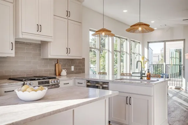 a kitchen with stainless steel appliances granite countertop a sink a stove and a granite counter tops with white cabinets