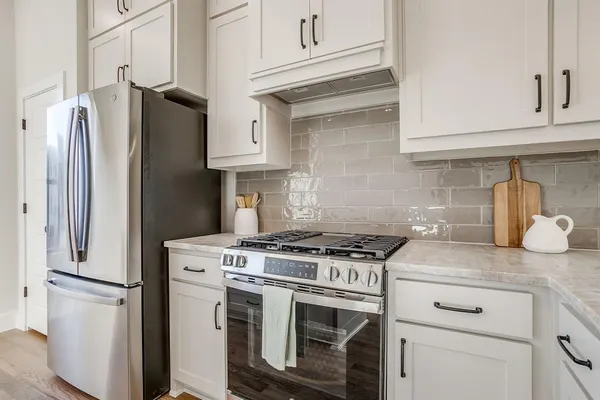 a kitchen with stainless steel appliances granite countertop white cabinets a refrigerator and a stove
