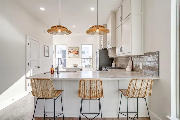 a kitchen with stainless steel appliances a dining table chairs and a refrigerator