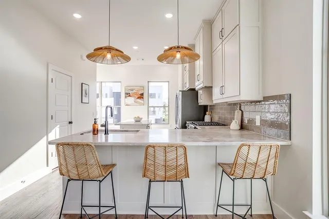 a kitchen with stainless steel appliances a dining table chairs and a refrigerator