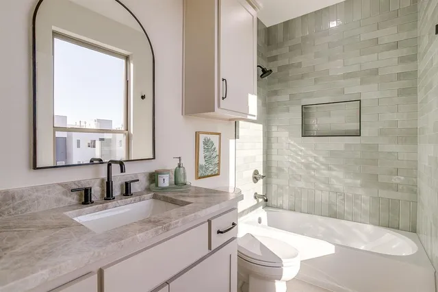 a bathroom with a granite countertop sink a toilet and bathtub