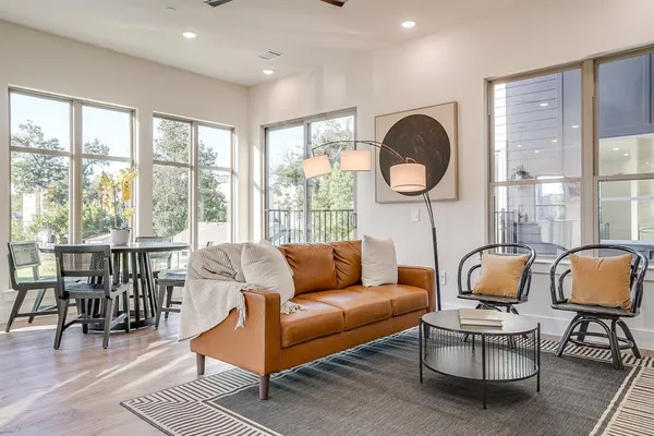 a living room with furniture a rug potted plant and a large window