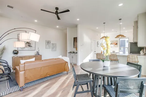 a living room with stainless steel appliances furniture a dining table and a chandelier