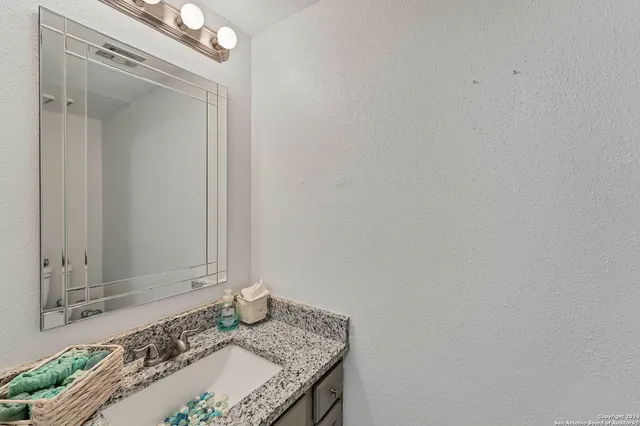 a bathroom with a granite countertop sink and a mirror