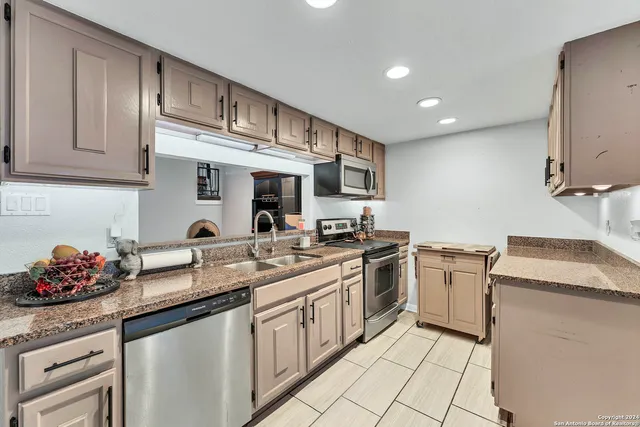 a kitchen with granite countertop a sink stainless steel appliances and cabinets