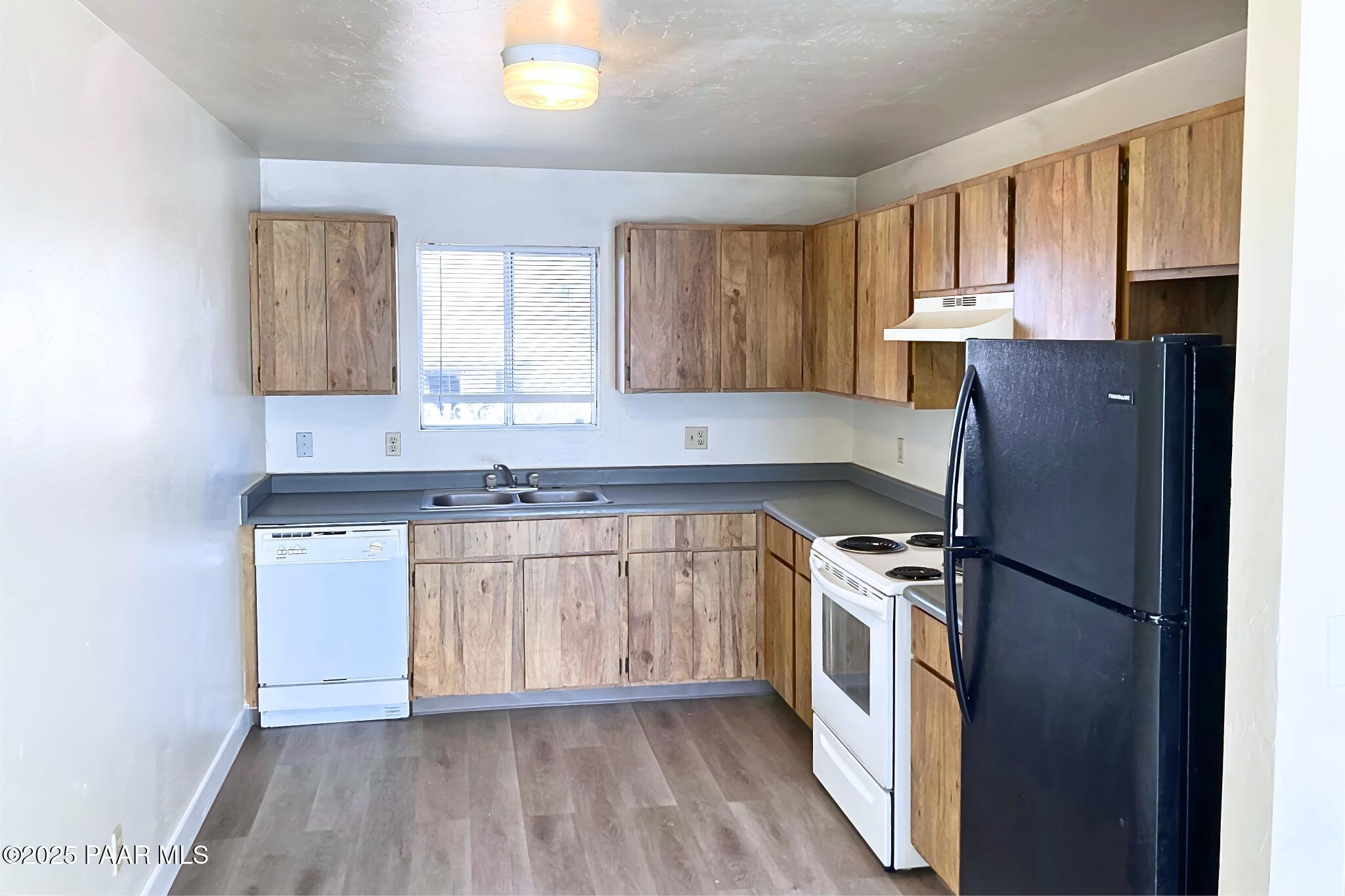 3184 North Tani Road, Unit 12 Prescott Valley, AZ 86314 - Photo 4 of 8 a kitchen with stainless steel appliances granite countertop a refrigerator a sink dishwasher a stove with wooden cabinets and floor