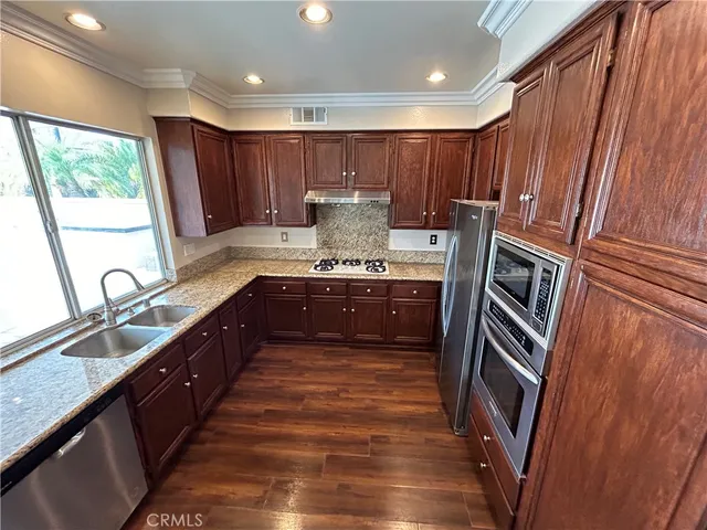 a large kitchen with granite countertop a sink and dishwasher a stove top oven with wooden floor