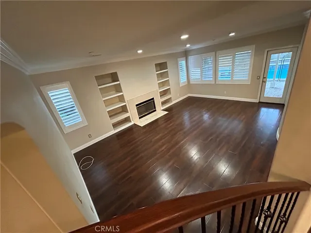 a view of an empty room with a window and wooden floor