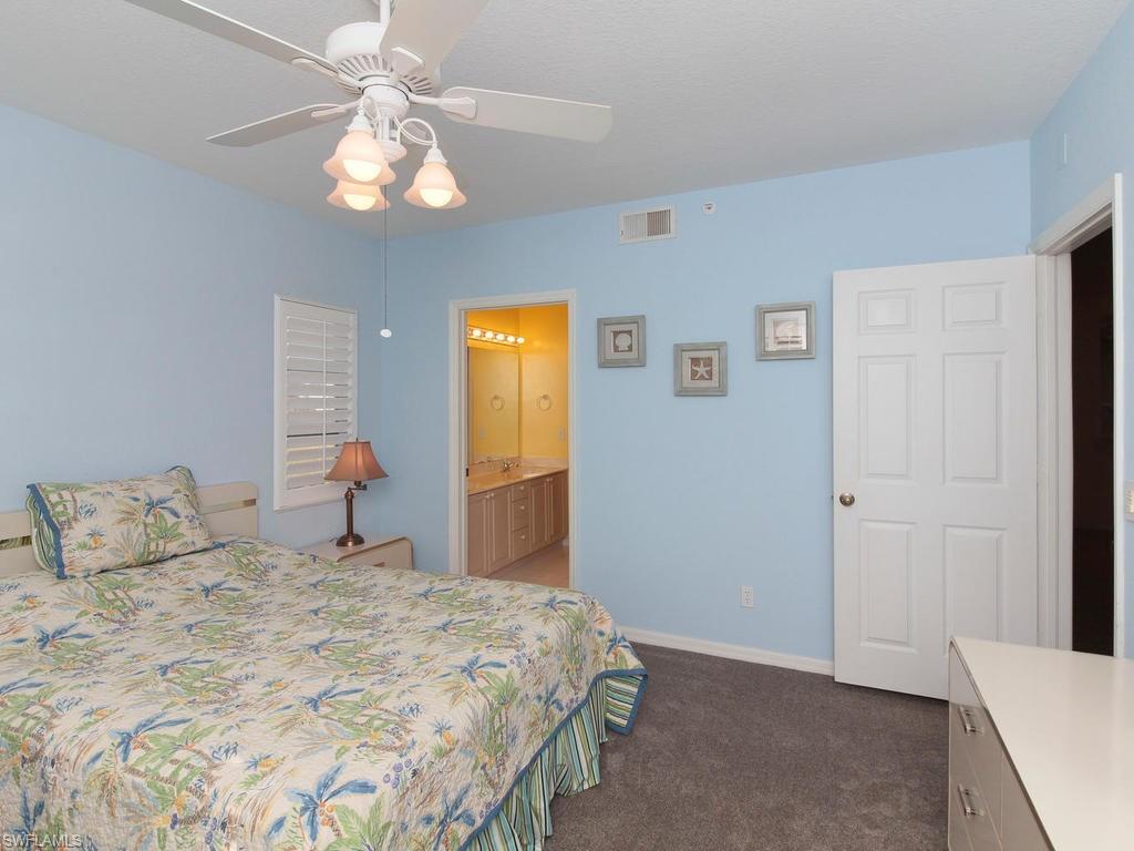 550 Gabriel Circle, Unit 3111 Naples, FL 34104 - Photo 22 of 25 a bedroom with a bed and a chandelier