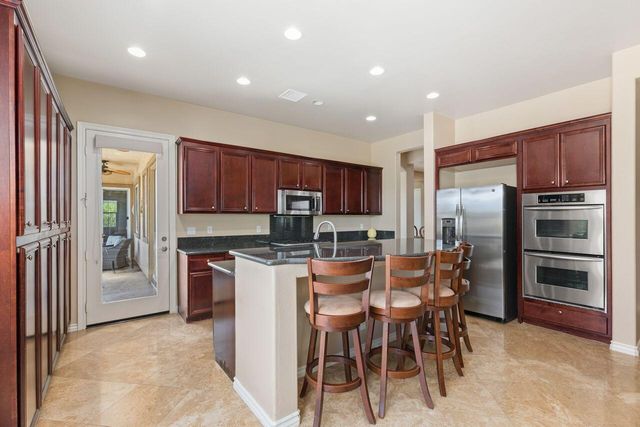 a kitchen with stainless steel appliances kitchen island granite countertop a refrigerator and a stove top oven