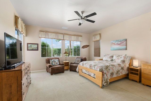 a living room with a bed furniture flat screen tv and a large window