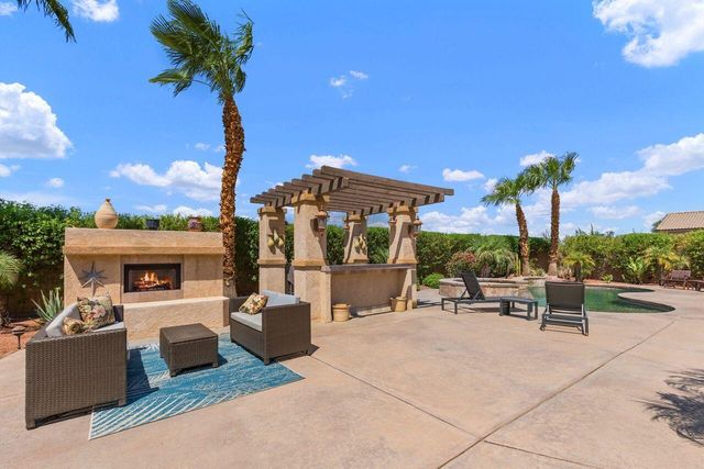 a view of a patio with couches and table and chairs under an umbrella with a fire pit
