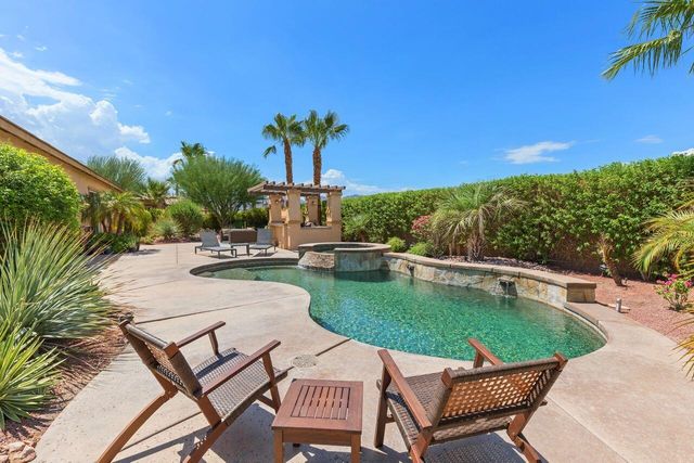 a view of a swimming pool with lawn chairs potted plants and palm tree