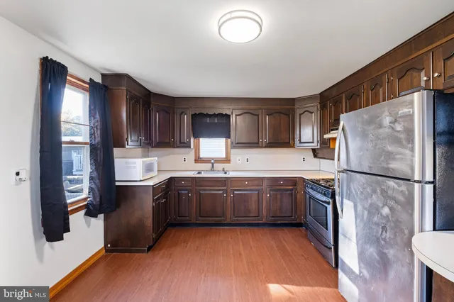 a kitchen with stainless steel appliances granite countertop a refrigerator a sink dishwasher a stove with wooden cabinets and floor