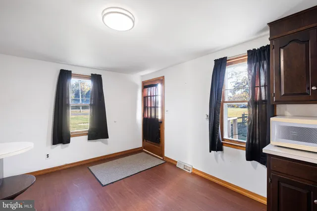 a view of an empty room with window and wooden floor