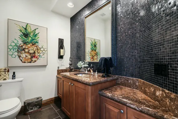 a bathroom with a granite countertop sink vanity mirror and toilet