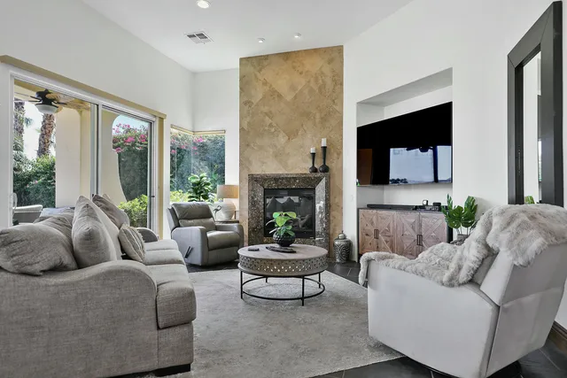 a living room with furniture a fireplace and a floor to ceiling window