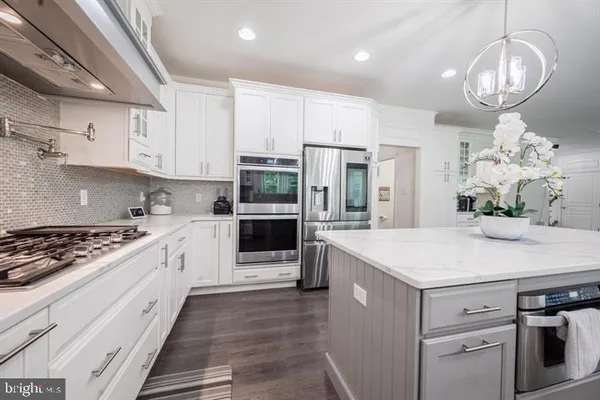 a kitchen with kitchen island granite countertop stainless steel appliances a stove refrigerator and cabinets