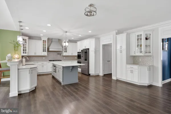 a large kitchen with a large counter top space a sink stainless steel appliances and cabinets