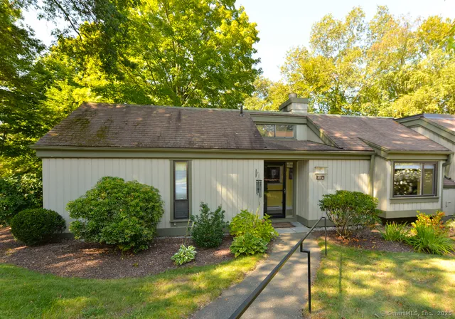 a view of a house with brick walls plants and large tree