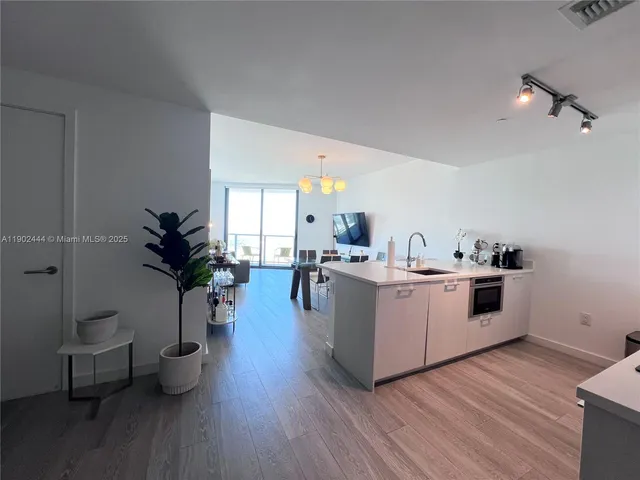 a kitchen with a white stove top oven and potted plant with wooden floor