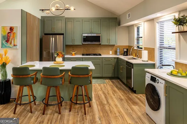 a kitchen with stainless steel appliances granite countertop a stove a sink dishwasher and a refrigerator with wooden floor