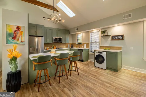 a kitchen with stainless steel appliances a stove a refrigerator a sink dishwasher and a dining table with wooden floor