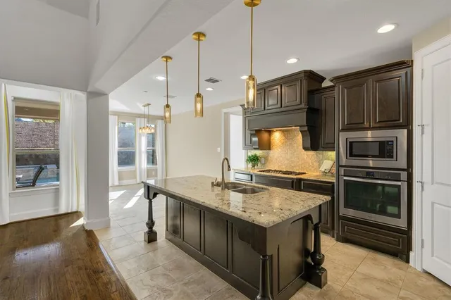 a kitchen with stainless steel appliances granite countertop a kitchen island a stove and a sink