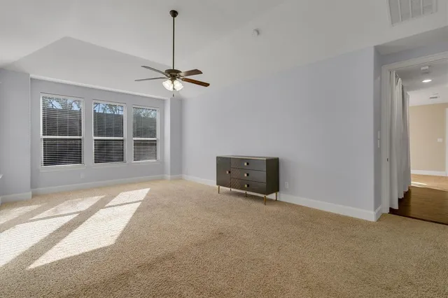 a view of an empty room with a window and ceiling fan
