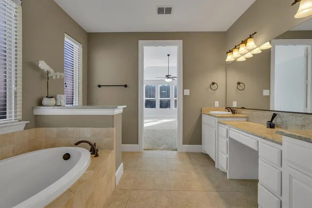 a spacious bathroom with a tub sink and mirror