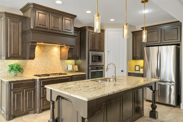 a kitchen with stainless steel appliances granite countertop a kitchen island a stove a refrigerator and a refrigerator