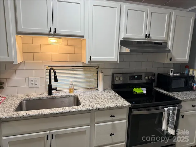 a kitchen with granite countertop a sink a stove and cabinets