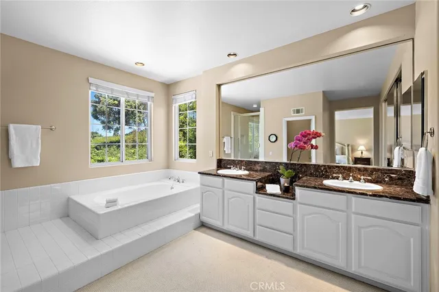 a spacious bathroom with a double vanity sink a mirror and a bathtub
