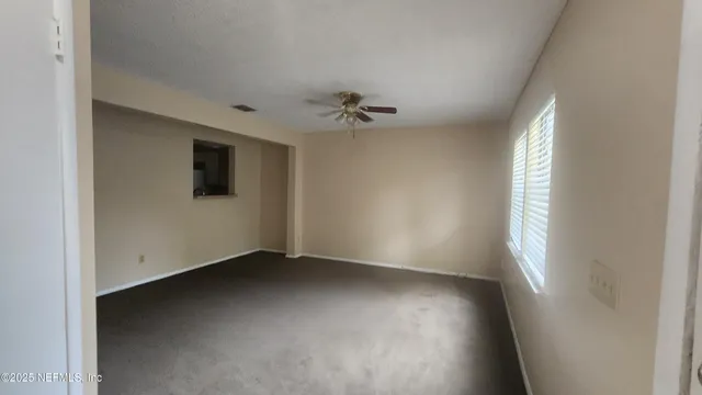 an empty room with windows and ceiling fan