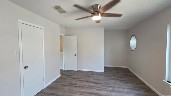 an empty room with wooden floor fan and window