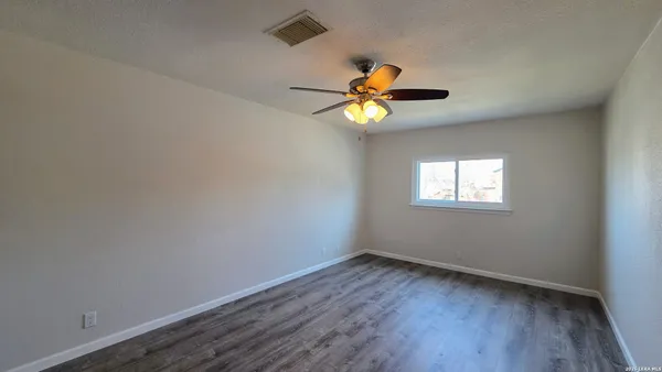 an empty room with wooden floor and window