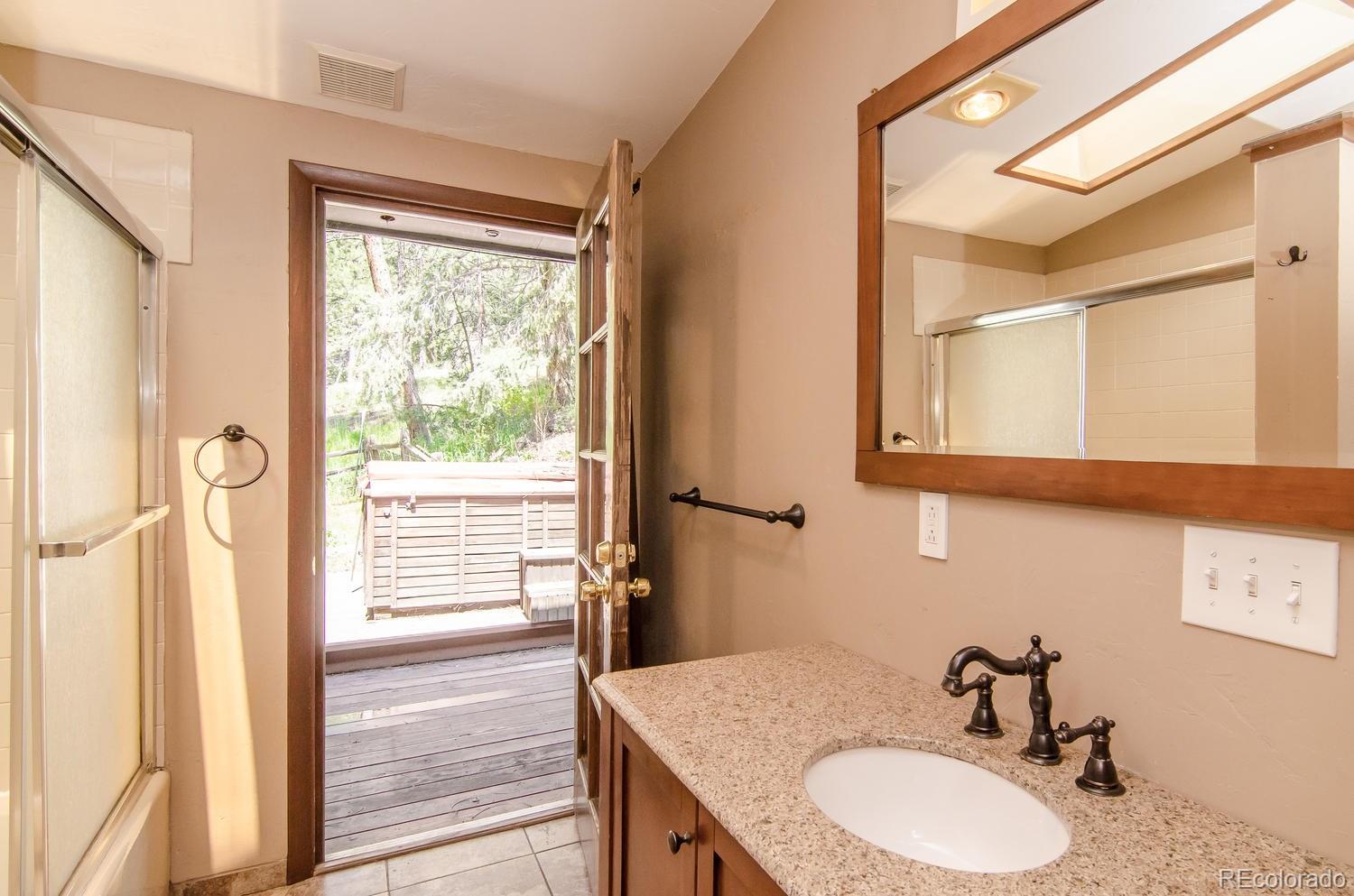31463 Upper Bear Creek Road Evergreen, CO 80439 - Photo 12 of 23 a bathroom with a granite countertop sink and a mirror