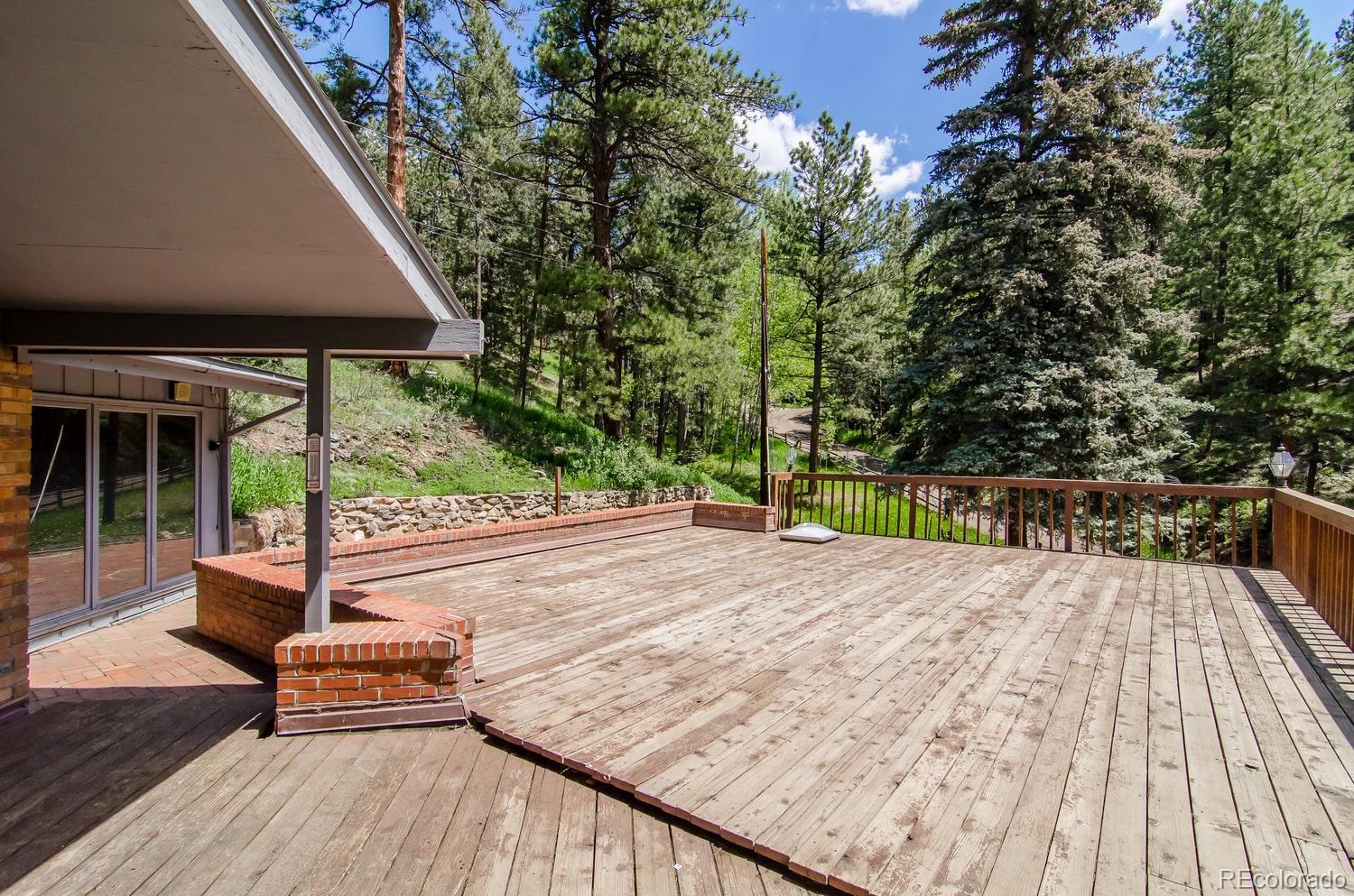 31463 Upper Bear Creek Road Evergreen, CO 80439 - Photo 22 of 23 a patio with table and chairs and potted plants with wooden floor and fence