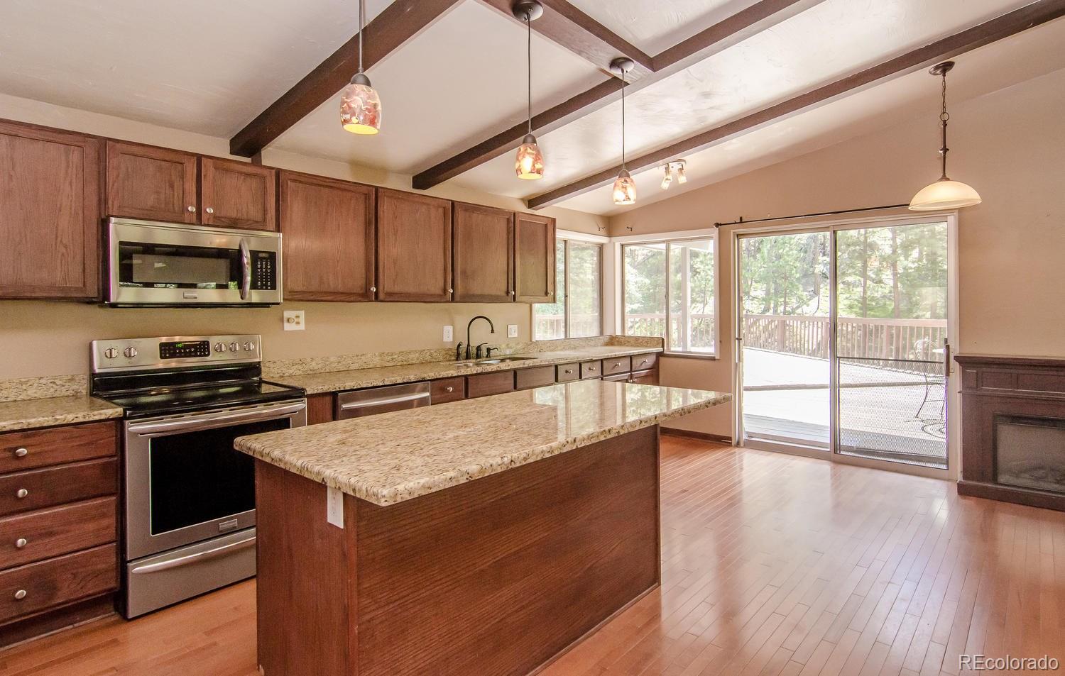31463 Upper Bear Creek Road Evergreen, CO 80439 - Photo 10 of 23 a kitchen with stainless steel appliances granite countertop a stove a sink and a microwave