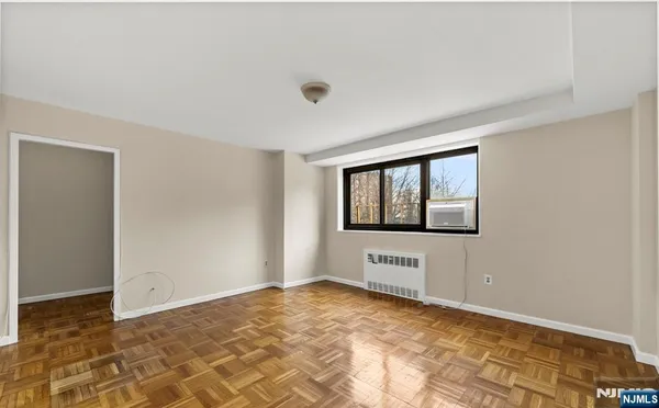 a view of an empty room with window and chandelier fan