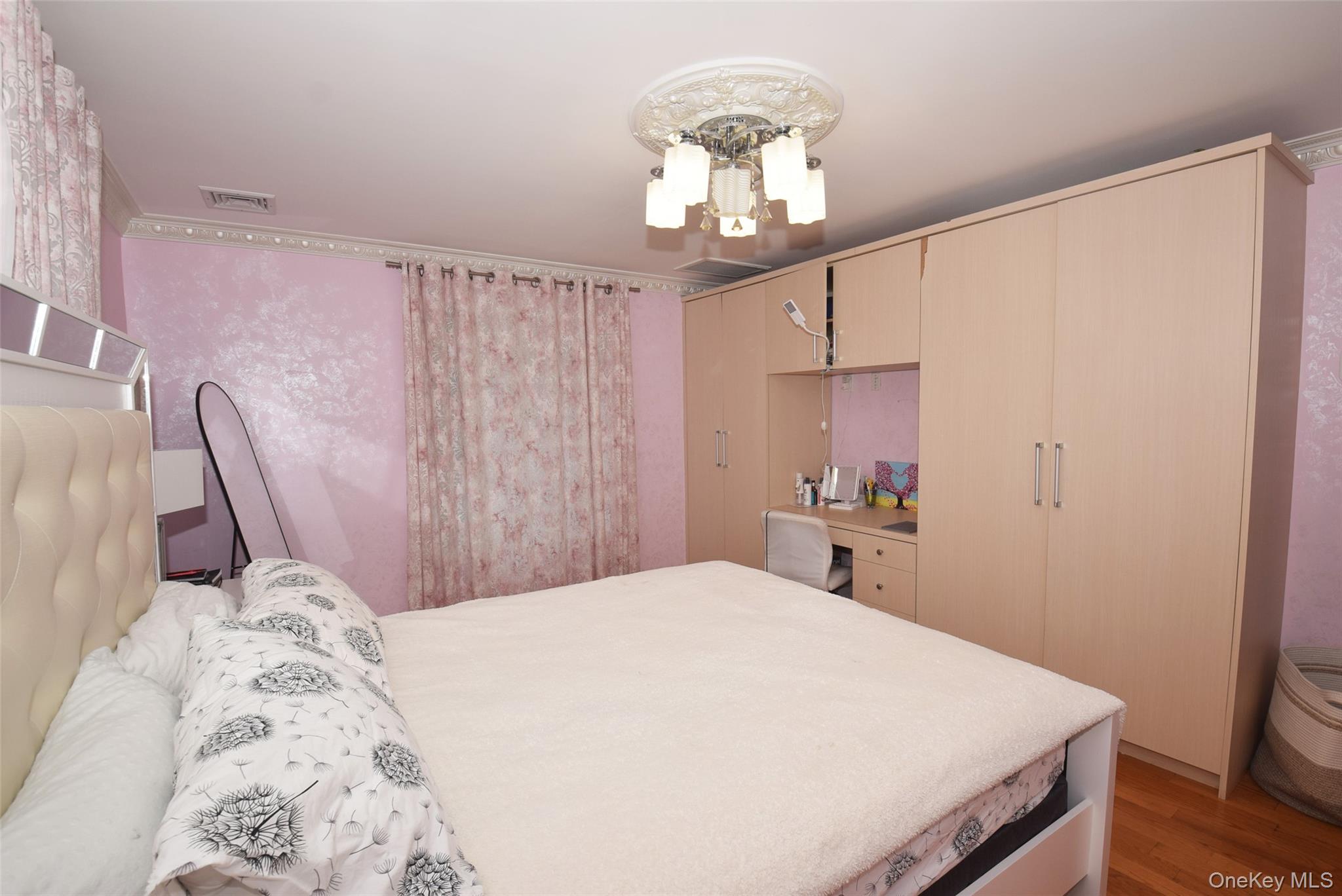 1-10 82nd Avenue Queens, NY 11415 - Photo 26 of 50 a bedroom with a large bed and a chandelier