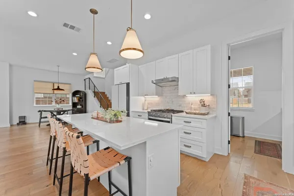 a kitchen with stainless steel appliances a table chairs and a wooden floor