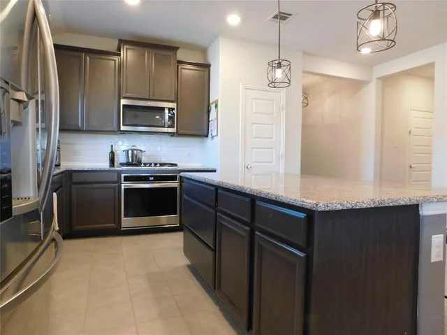 a kitchen with stainless steel appliances granite countertop a sink a stove and a refrigerator
