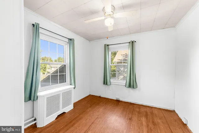 an empty room with wooden floor fan and windows